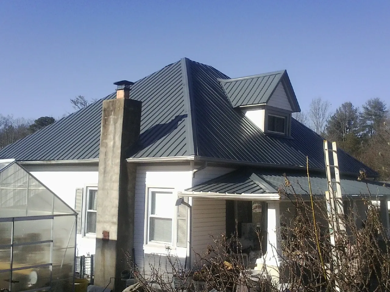 Dark blue standing seam metal roof on a white farmhouse with dormer — Slate & Tile Roof Repair by Roofing Brothers in Havana