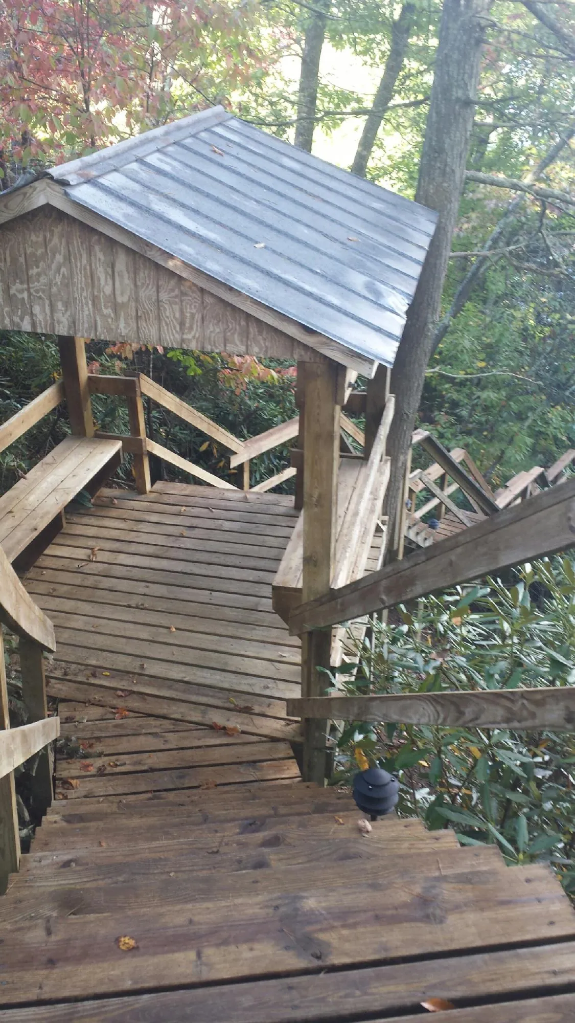Metal roofed shelter over wooden steps on a wooded walkway — Skylight Repair & Installation work by our crew in Havana